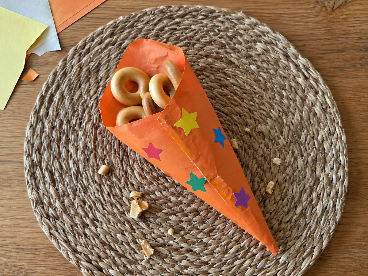 Кулёк-конус из оранжевой бумаги, украшенный наклейками со звёздочками, внутри несколько сушек